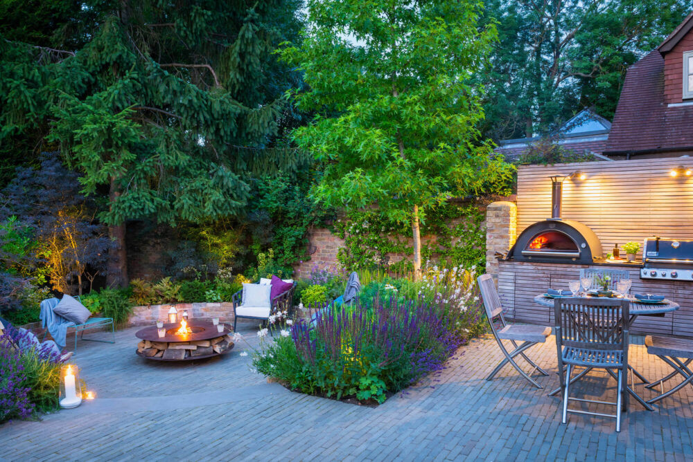 Outdoor entertaining area with planting sectioning a seated firepit area and a dining area